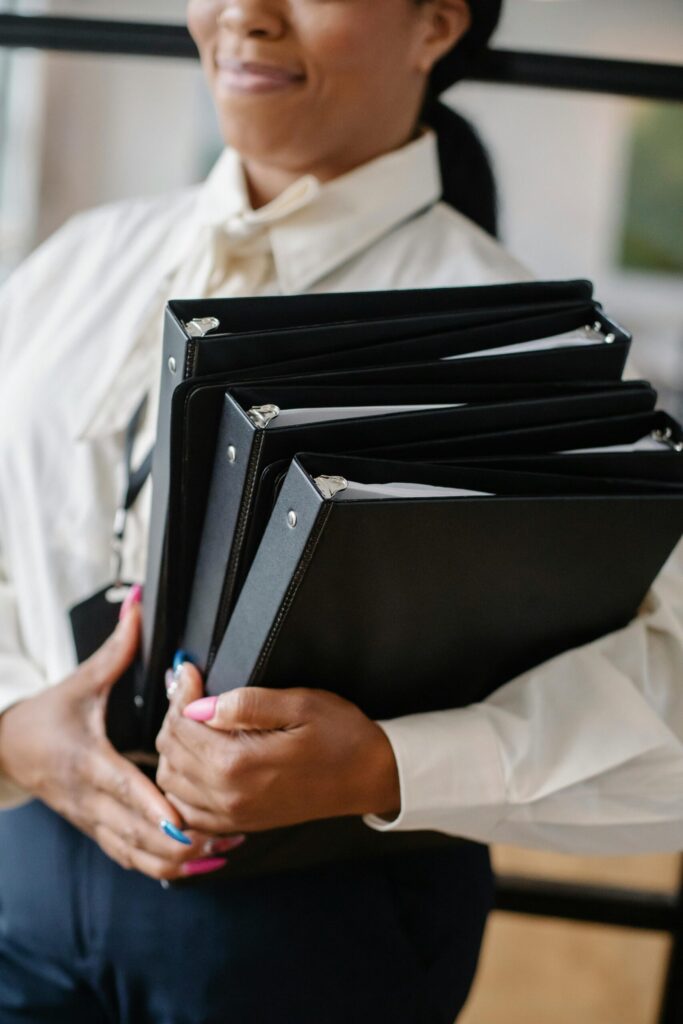 Person holding 3 black binders